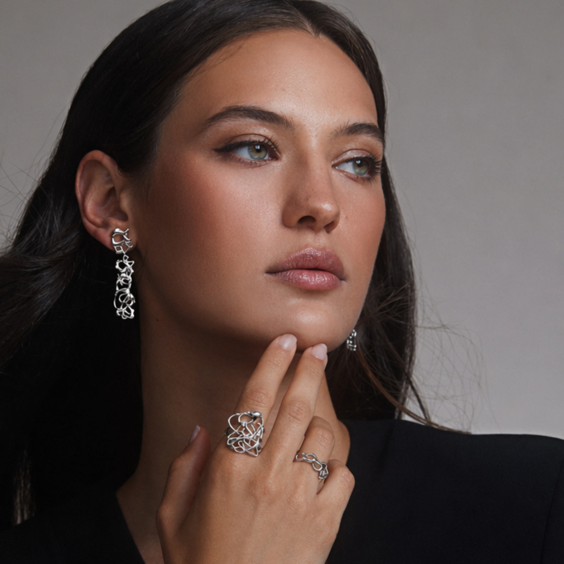 model wearing organic and fluid cocktail statement ring in silver with matching earrings by jessica liu