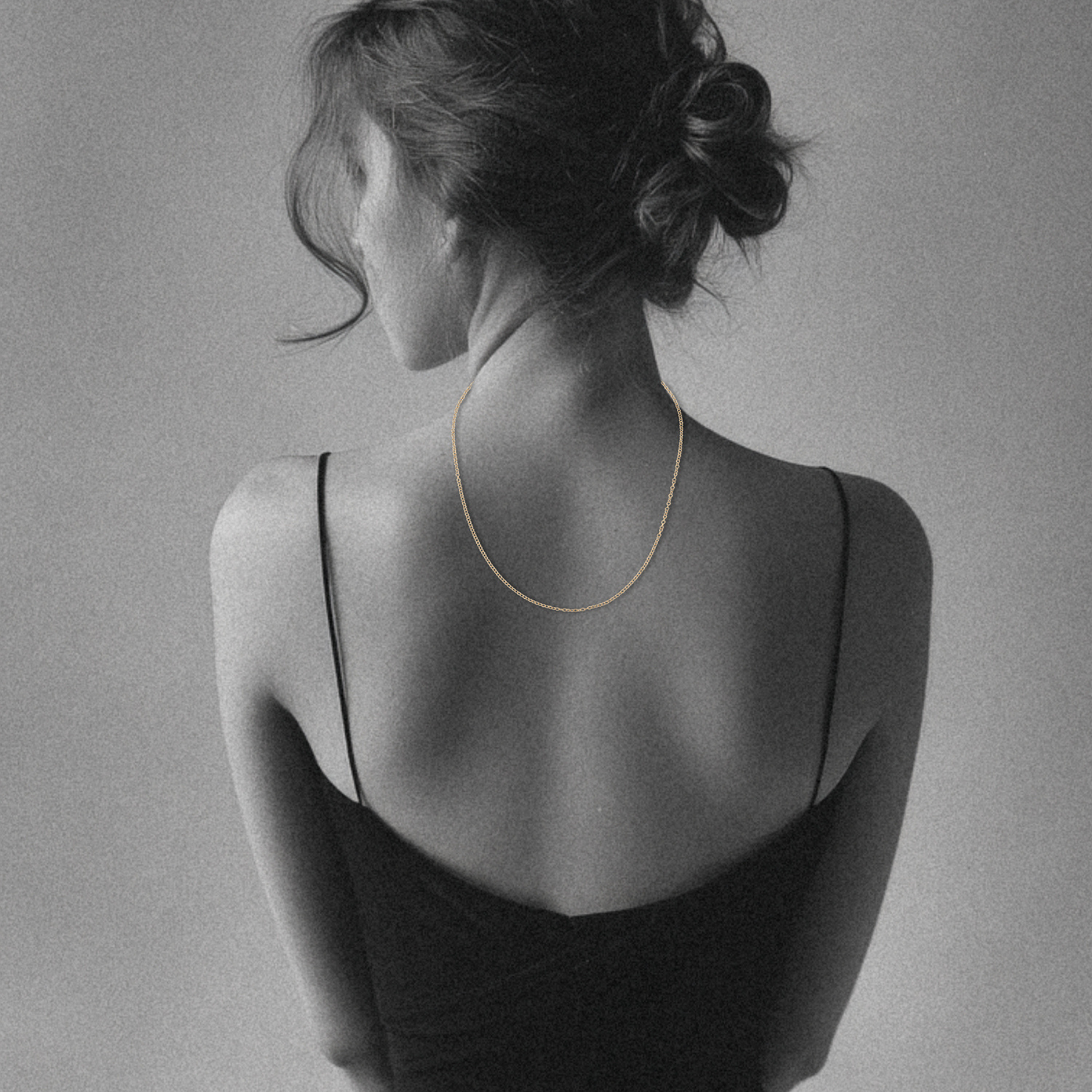 woman's back draped with delicate 14k gold cable chain