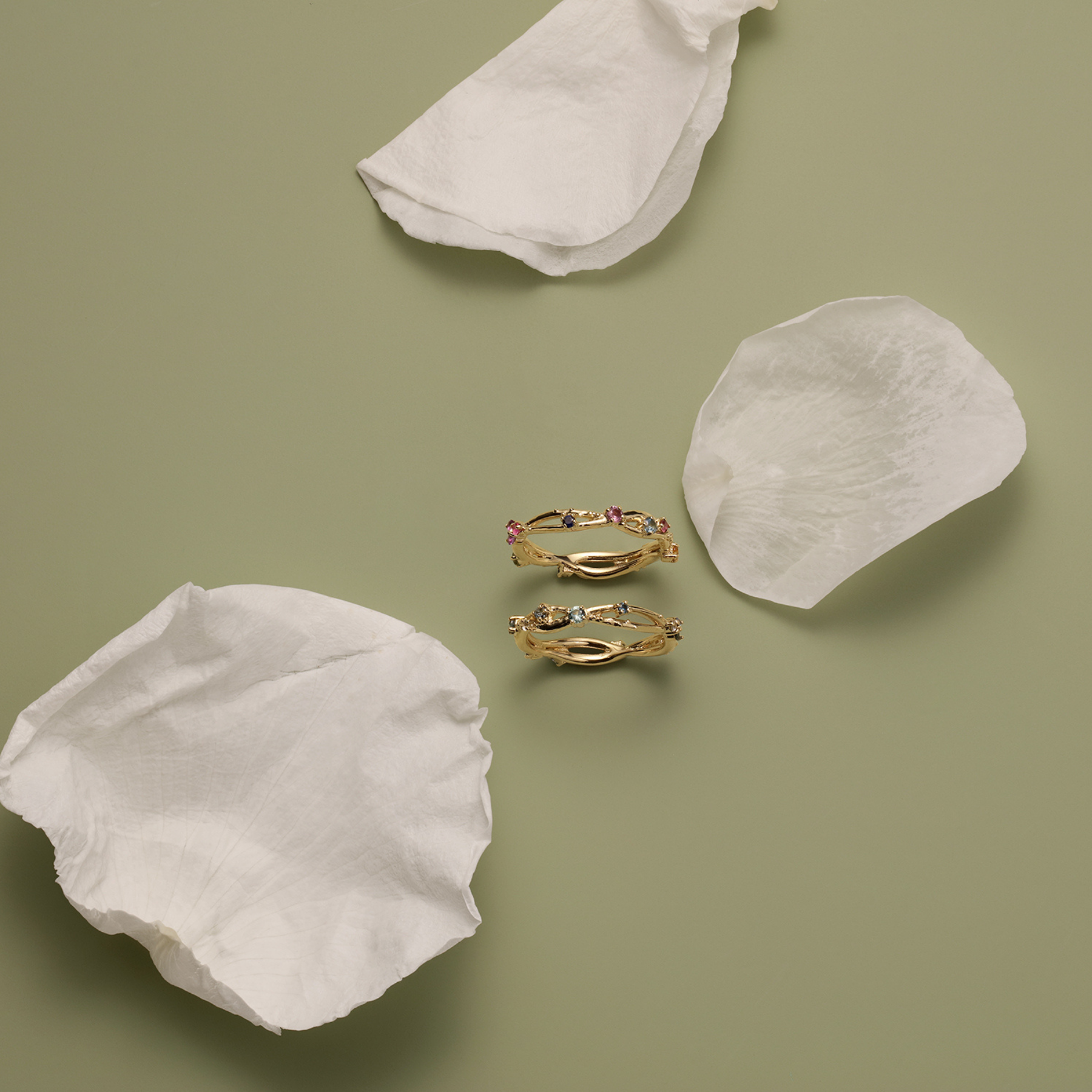 flat lay of organic interweaving ring bands with multicolored stones by jessica liu
