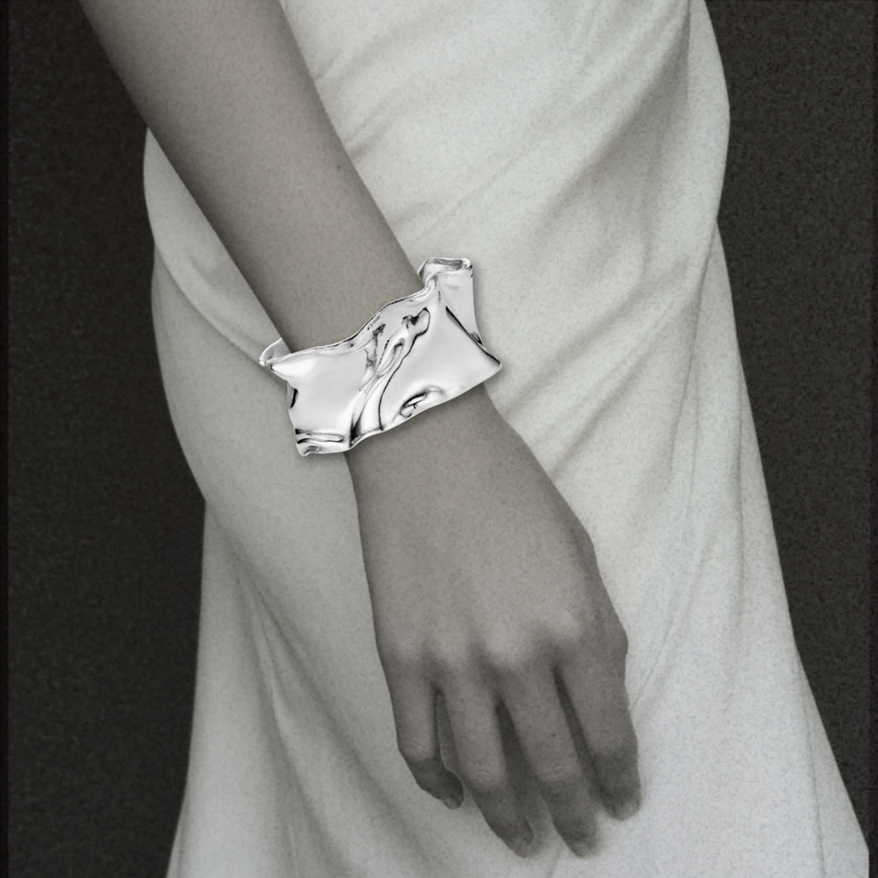sculptural organic ribbon statement cuff bracelet in sterling silver on woman's wrist by jessica liu