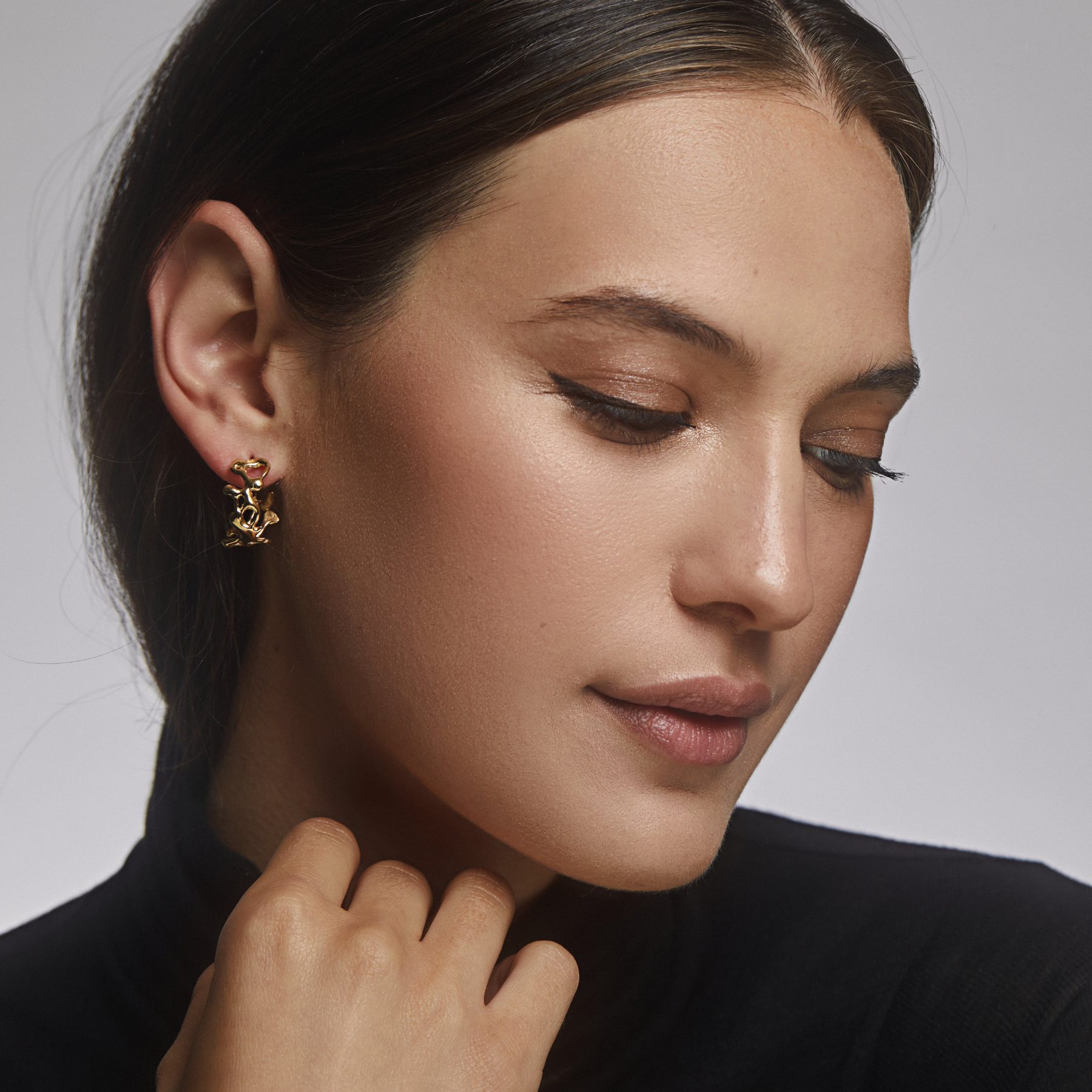 model wearing 14k gold abstract fluid asymmetrical small hoop earrings by jessica liu