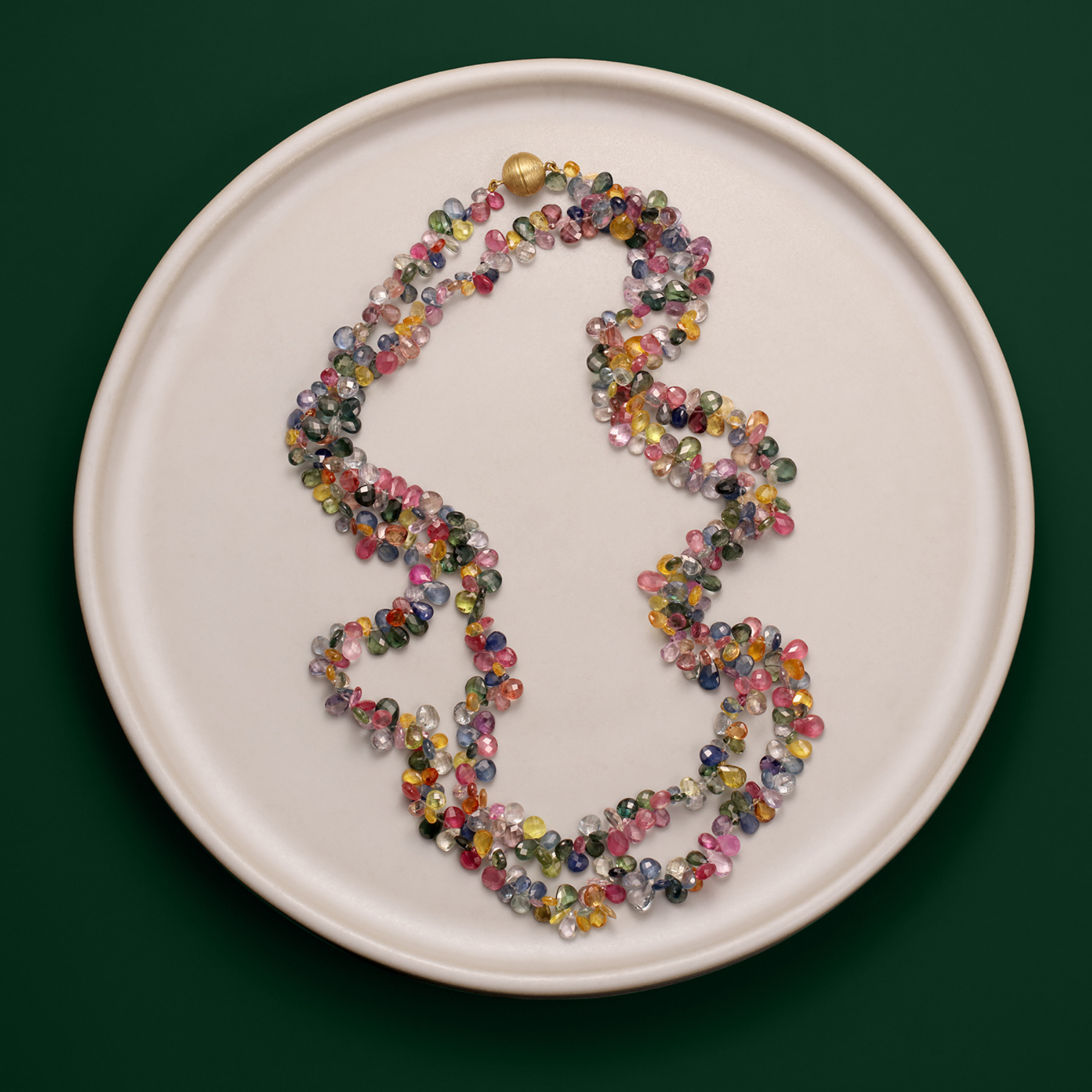 white plate with extra long multicolored sapphire gemstone necklace with a 14k gold ball clasp double layered by jessica liu