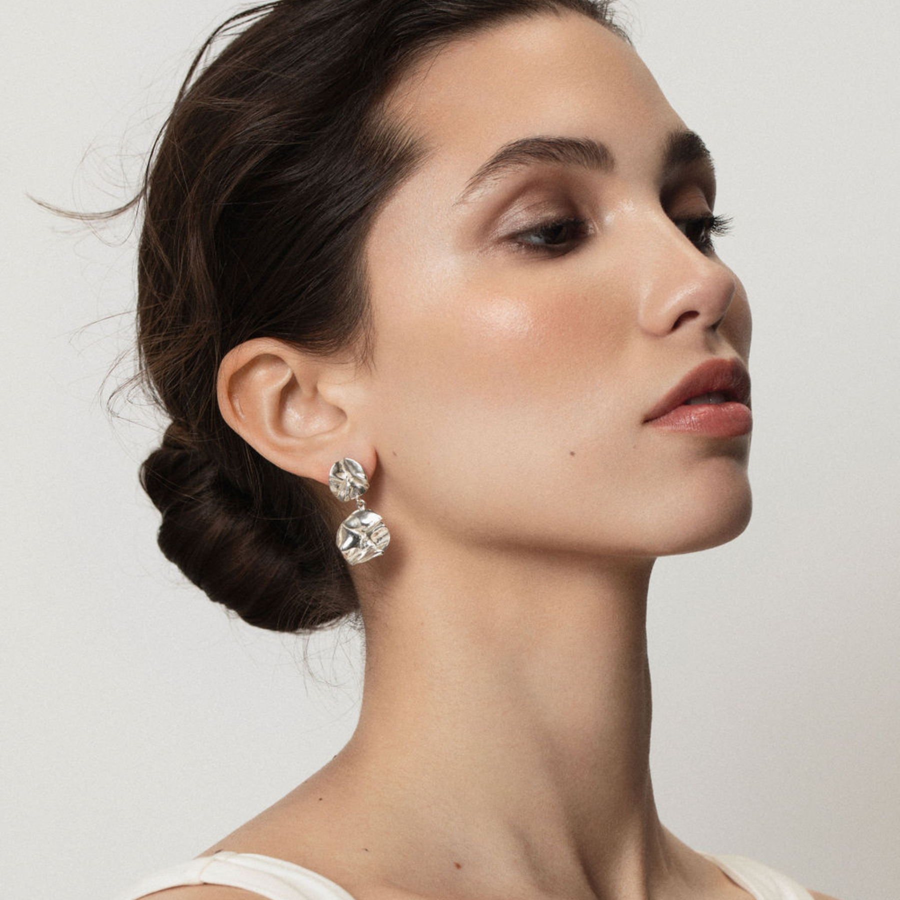 woman wearing sculptural double lilypad dangling earrings in silver by jessica liu
