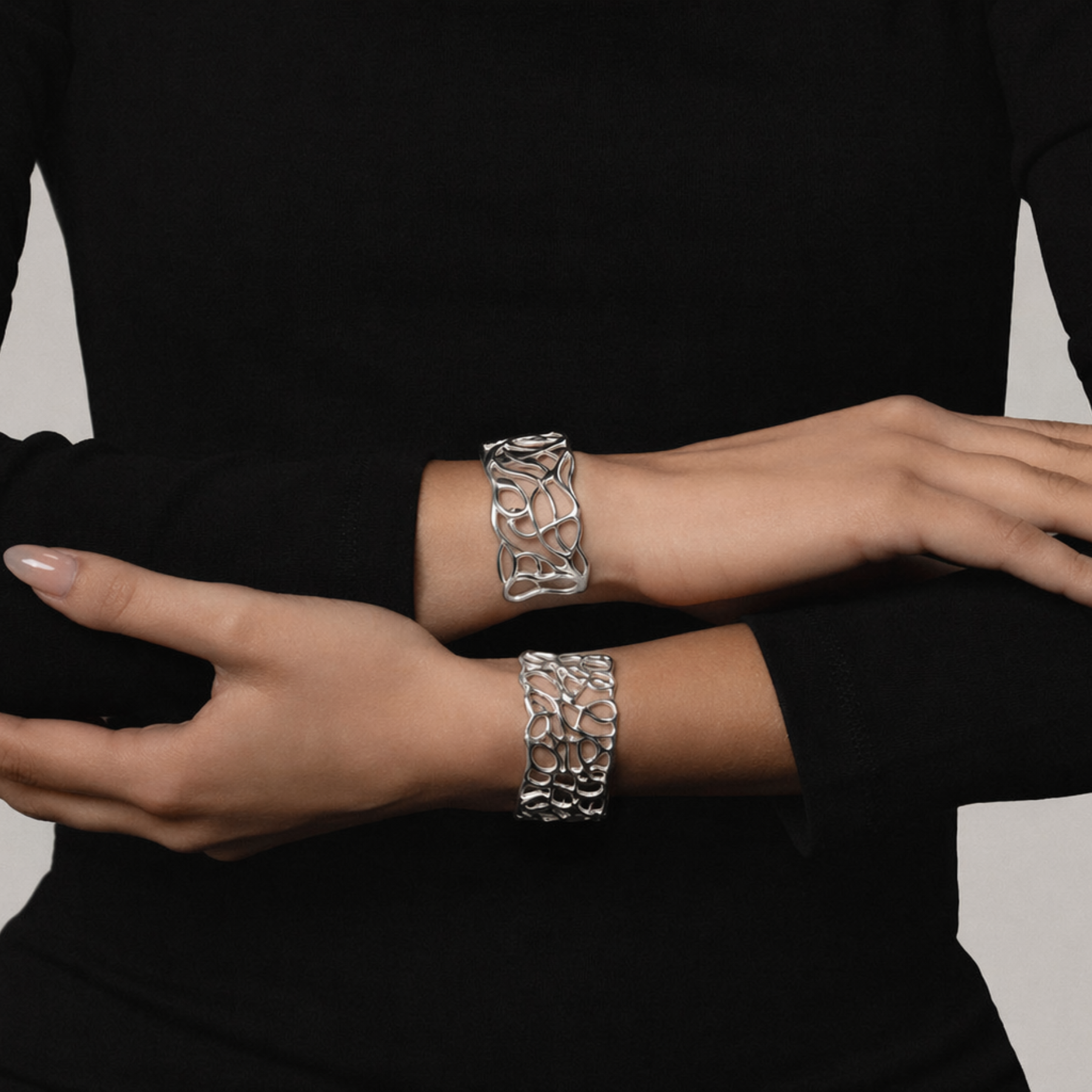 model's wrists showing artful fluid lines cuff bracelet in silver with second organic cuff by jessica liu