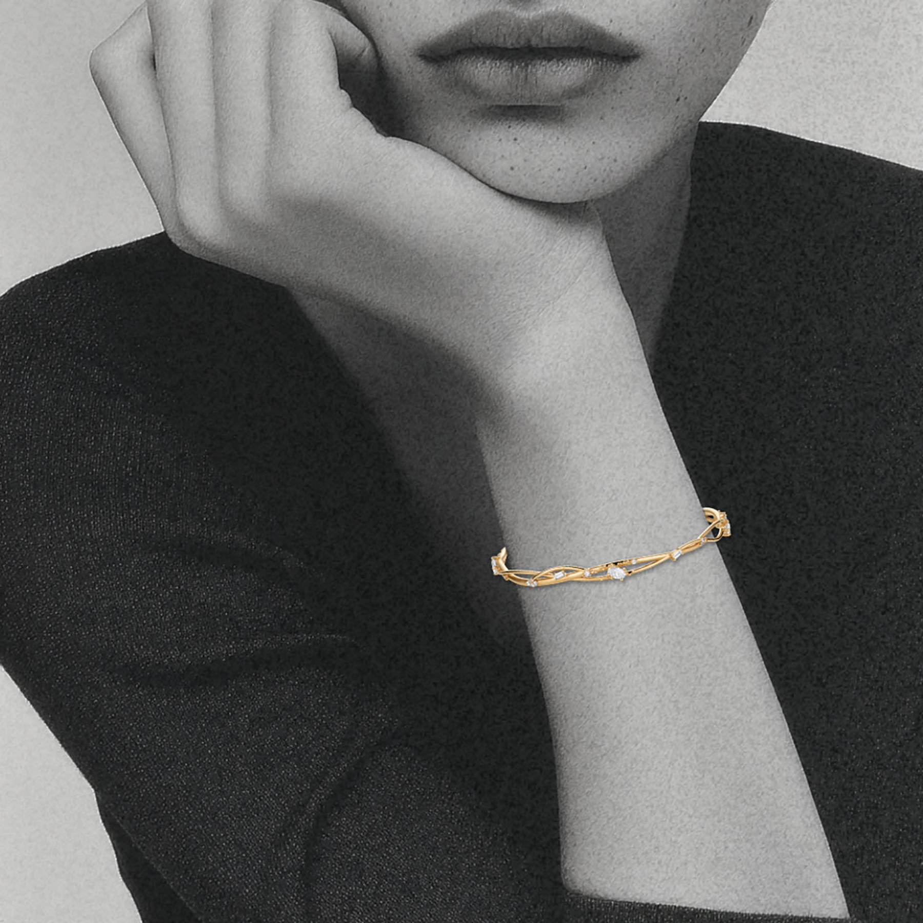 woman's wrist featuring organic interweaving bangle in 14k gold studded with white diamonds by jessica liu