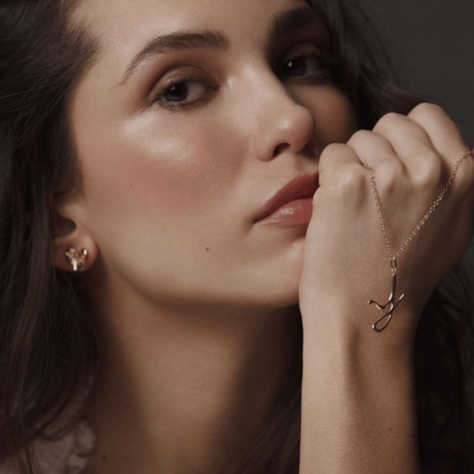 model holding a 14k gold letter j necklace by jessica liu