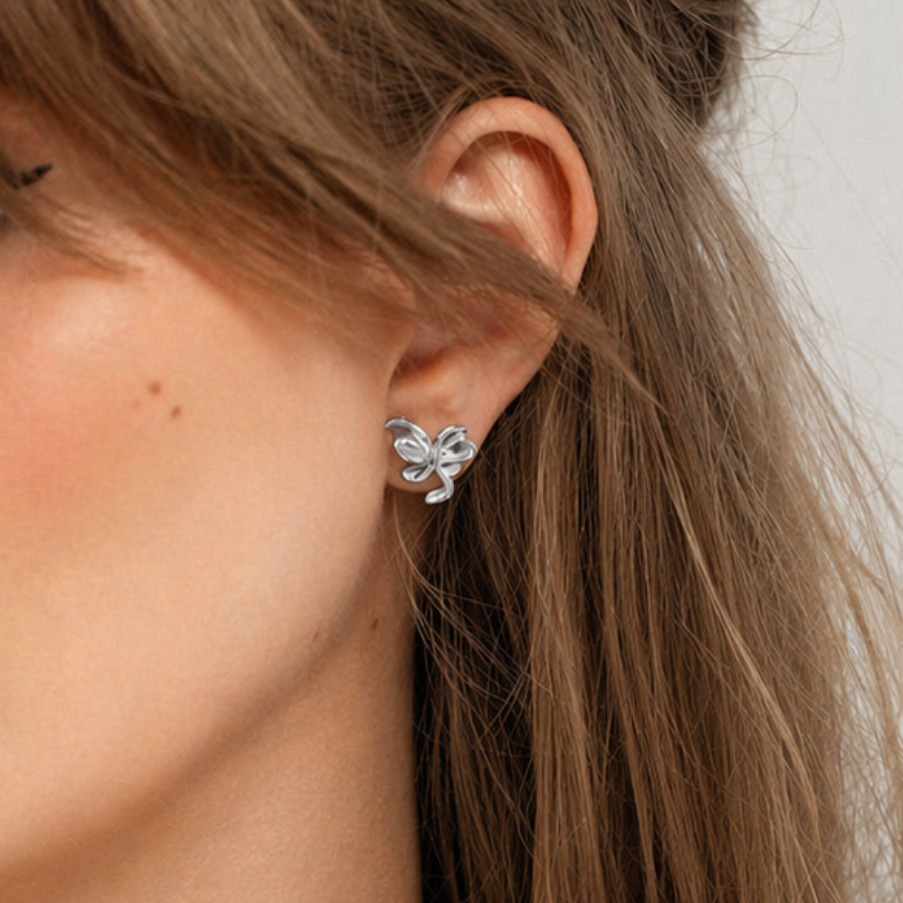 closeup of model wearing organic lily flower stud earrings in silver by jessica liu