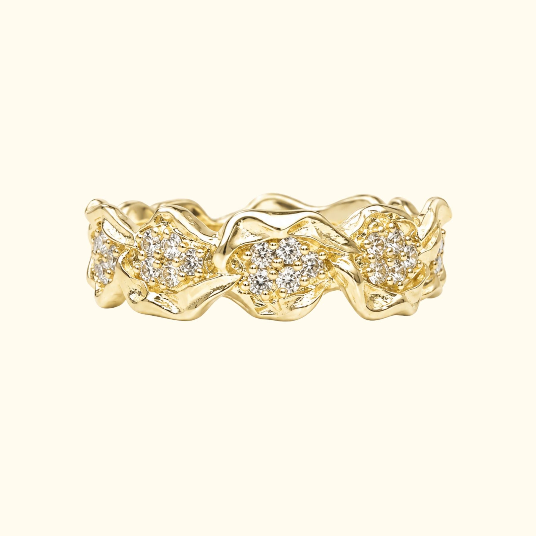 A gold band ring by Jessica Liu featuring textured, organic-shaped clusters of small pavé-set diamonds, shown on a light cream background.