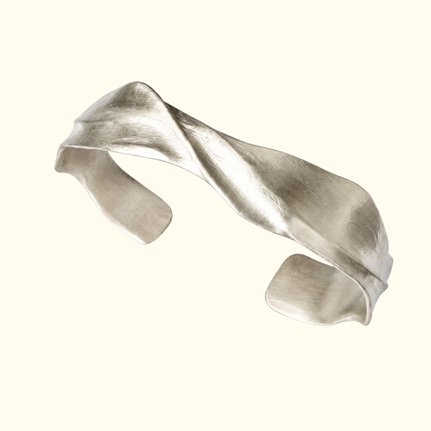 A sculptural silver cuff bracelet by Jessica Liu with a twisted, organic wavy design, shown on a solid cream background.